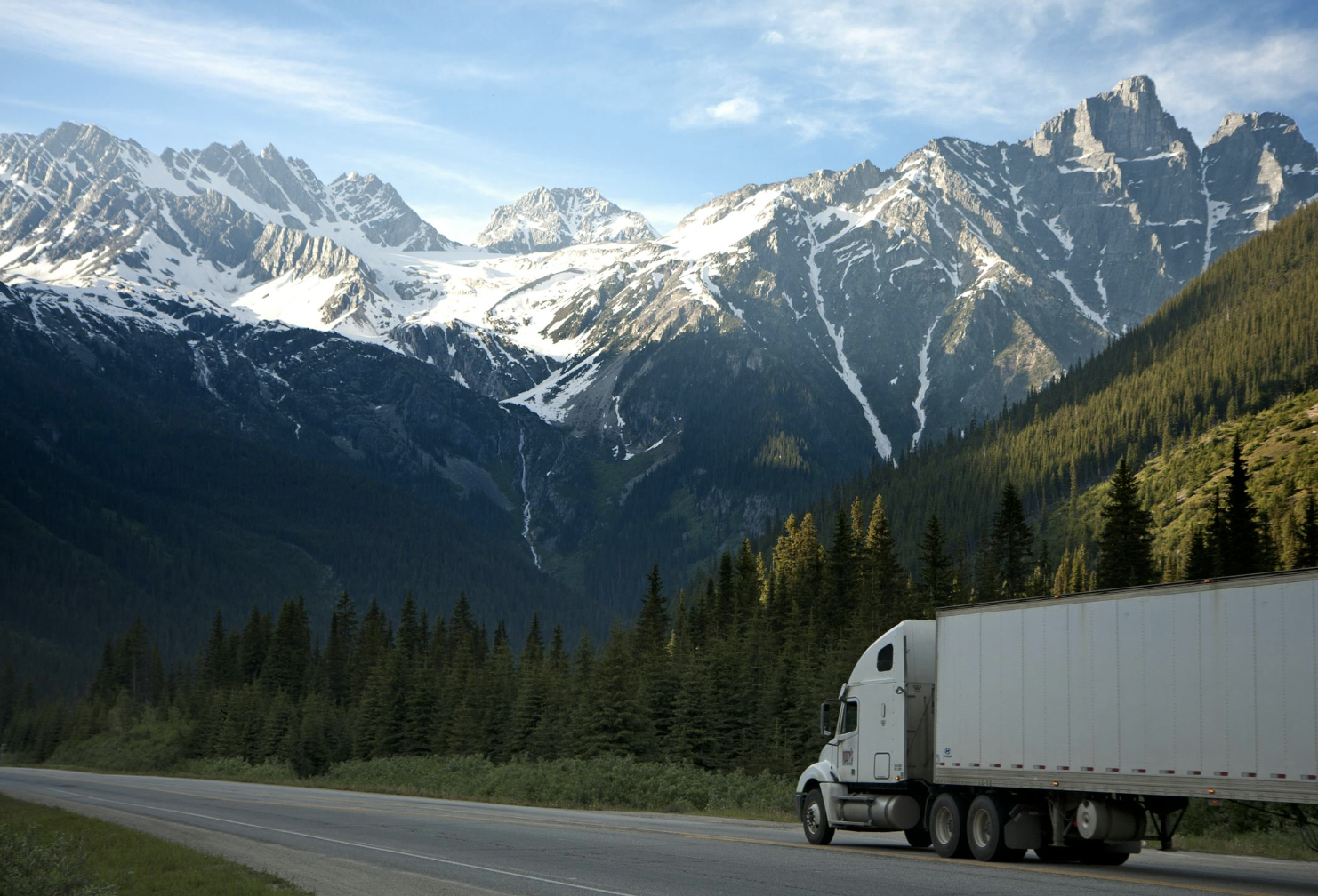 semi truck driving toward a mountain range